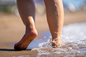 Closeup of woman feet walking on sand beach.