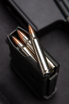 Close-up of .223 carbine cartridges. Loaded weapon clip. Weapons in the back