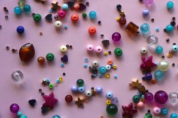 Various colorful beads on bright pink background. Top view.