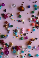 Various colorful beads on bright pink background. Top view.