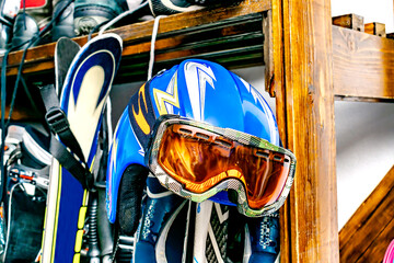 Helmet, ski mask, ski hanged on customized wooden wall mount at warehouse for seasonal storage at ski resort. Extreme winter sport equipment handling at home - obrazy, fototapety, plakaty
