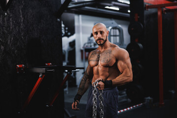 Fototapeta na wymiar Male Athlete Standing In The Gym With Heavy Chains