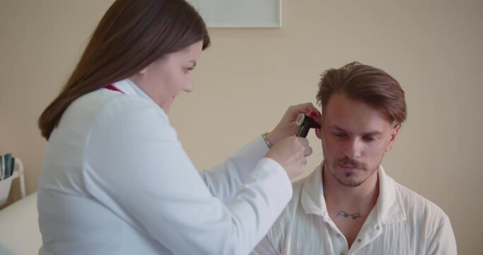 Female doctor using video otoscope checking patient ears at the clinic room.