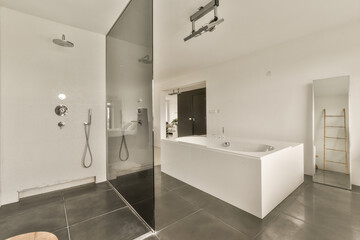a modern bathroom with white walls and black tiles on the floor, there is a large mirror in the...