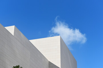 Modern architecture detail with blue sky and a single cloud, on a sunny day.