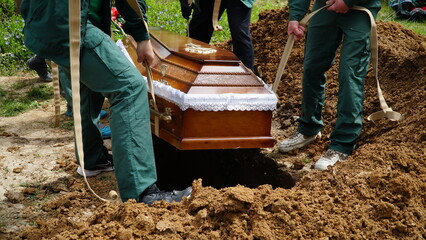 Burial. Men lower the coffin into the grave.