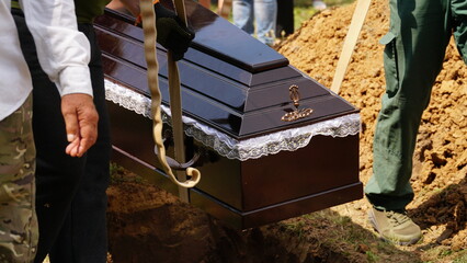 Burial. Men lower the coffin into the grave.