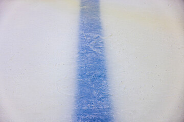 Close-up view of blue dividing line beneath intricately patterned surface of ice rink. Texture or...