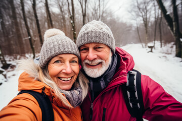 Fototapeta na wymiar portrait of happy senior couple taking selfie photo while enjoying hike in winter forest