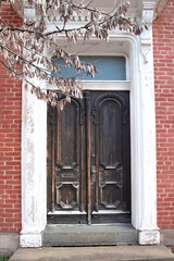 old, wooden, shabby front door to a brick house. concrete steps at the entrance.