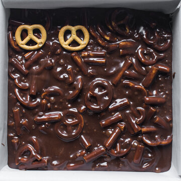 Top view of chocolate pretzel fudge in a baking tin, process of making chocolate pretzel fudge	