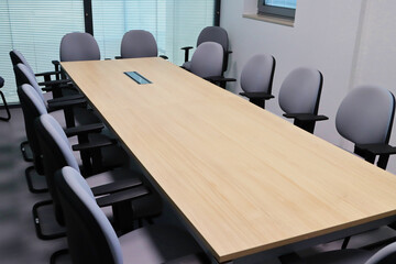 Meeting room of an office with wooden table and gray chairs. No people