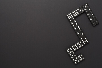 Black domino tiles on color background, top view