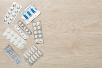 Pills in blister packaging on wooden background, top view