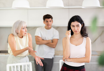 Upset woman dont speaking after discord with mother and husband standing behind