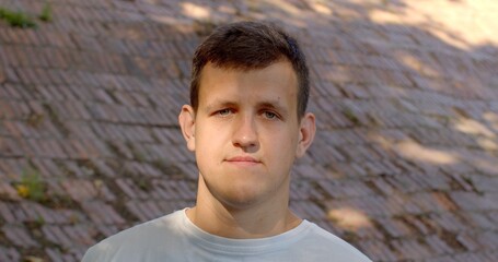 Young man gazes into the camera nodding in agreement. Close-up male portrait outside. Non-verbal...