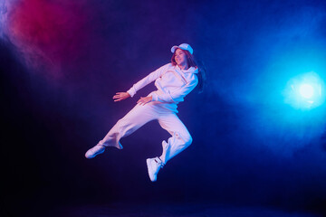 Fototapeta na wymiar a girl in light clothes dances on a neon background in smoke, modern dance