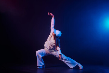 a girl in light clothes dances on a neon background in smoke, modern dance