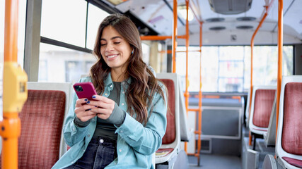 Happy young woman is using her mobile phone and enjoying the city