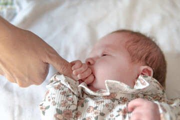 Newborn baby taking her mother's finger and putting it in her mouth to suck it. Concept of...