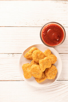 Top view of Chicken nugget on plate with ketchup on wooden table background.