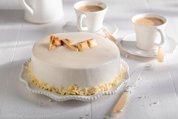 Sweet white chocolate cake served with coffee in white porcelain.