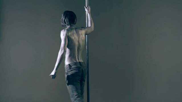 Flexible sexy body of young man. Pole dance. Sexy man exercise pole dance. Fit slim sexy man performs sensual pole dance. Go-go dancer. Strip dancer. Male athlete doing acrobatic trick on pylon.