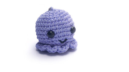 Amigurumi. Miniature octopus keychain in blue colors crocheted on a white background. Handmade crocheted soft keychain.