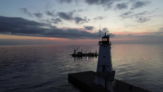 Ludington lighthouse on Lake Michigan. Aerial shot at the lightroom level circling the lighthouse. Features a dredge in the background, sunset, the city in the background, and the opposing beacon.