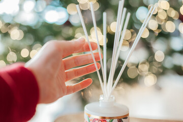  Christmas Scent.incense sticks in a hand on a Christmas tree background.Christmas atmosphere.Hands...