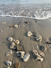 Sandy beach and white coral pebbles among the foam of the waves