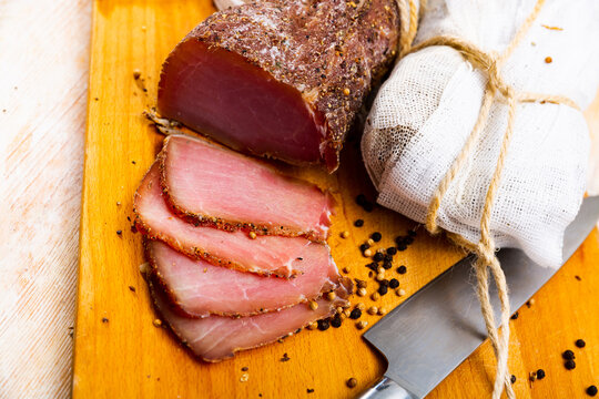 Sliced Polish cured sirloin pork polendvitsa on wooden cuting board. Traditional meat delicacies..