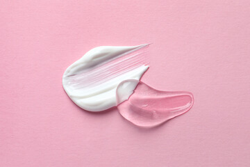 Samples of transparent gel and white cream on pink background, flat lay
