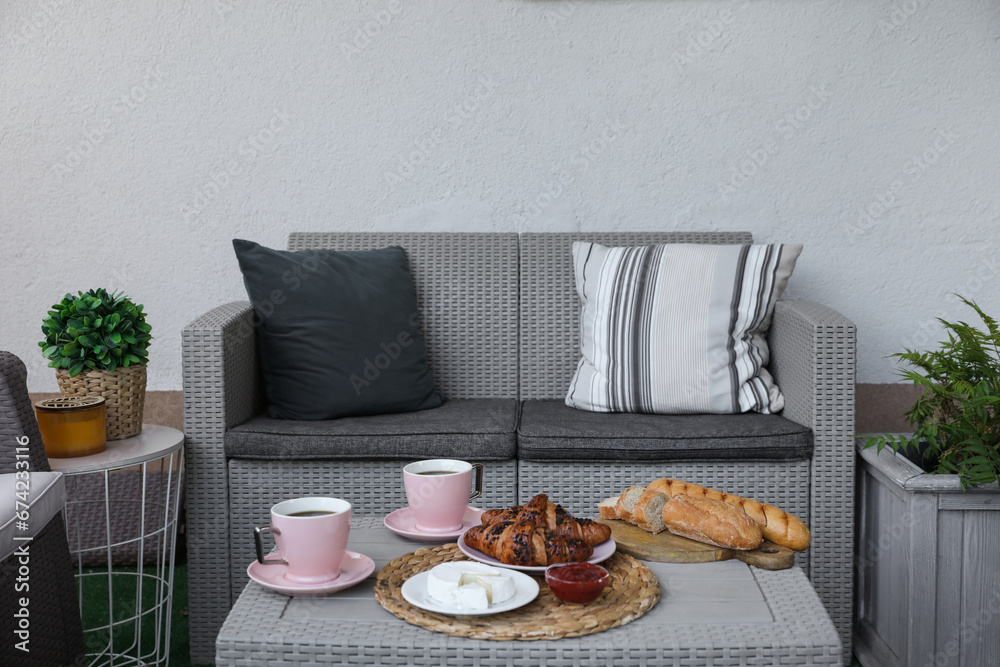 Canvas Prints Outdoor breakfast with tea and croissants on rattan table on terrace