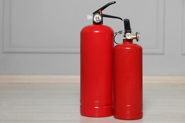 Red fire extinguishers near grey wall, space for text