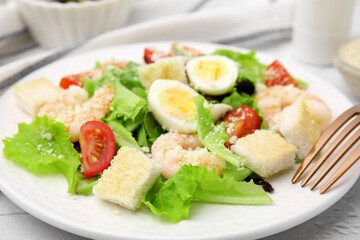 Delicious Caesar salad with shrimps and fork served on table, closeup