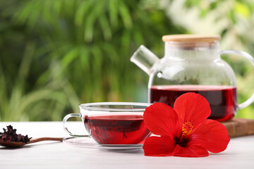 Delicious hibiscus tea and flowers on white wooden table outdoors, space for text