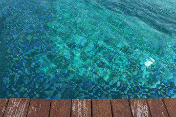 Clear rippled water in swimming pool and wooden deck outdoors