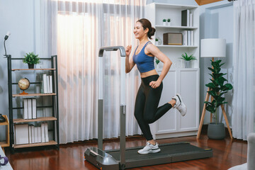 Fototapeta na wymiar Energetic and strong athletic asian woman running running machine at home. Pursuit of fit physique and commitment to healthy lifestyle with home workout and training. Vigorous