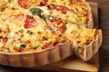 Tasty quiche with tomatoes and cheese on wooden table, closeup