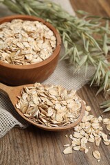Bowl, spoon with oatmeal and florets on wooden table, closeup