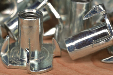 Zinc plated threaded tee nut fastener closeup. Woodworking fastener four prong nut.
