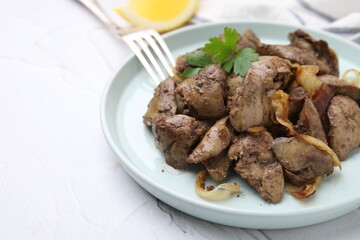 Tasty fried chicken liver with onion and fork on white textured table, space for text