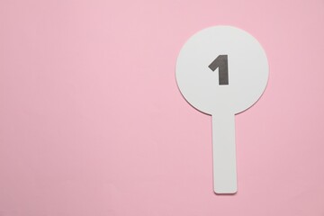 Auction paddle with number 1 on pink background, top view. Space for text