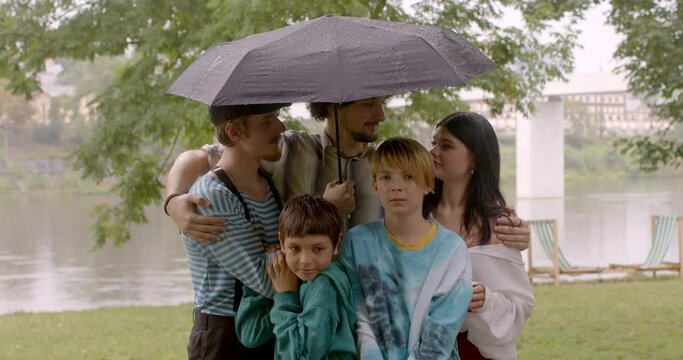 Sharing an umbrella in rainy weather among a group of young adults, kids and teenagers can symbolize a sense of unity, protection, and mutual support in human relationships. Providing comfort shelter.