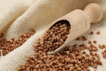 Scoop with dry buckwheat on white fabric, closeup