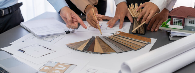 Group of interior designer team in meeting, discussing with engineer on interior design and planning for house project blueprint and model, choosing various mood board materials. Insight