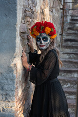 Young woman with painted skull on her face for Mexico's Day of the Dead (El Dia de Muertos) against color background
