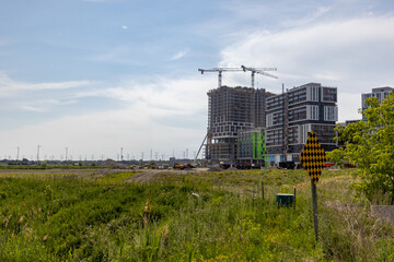 Fototapeta na wymiar Construction site - cranes - buildings - greenery - blue sky