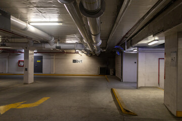Empty parking garage - concrete structure - yellow lines - pipes - exit sign